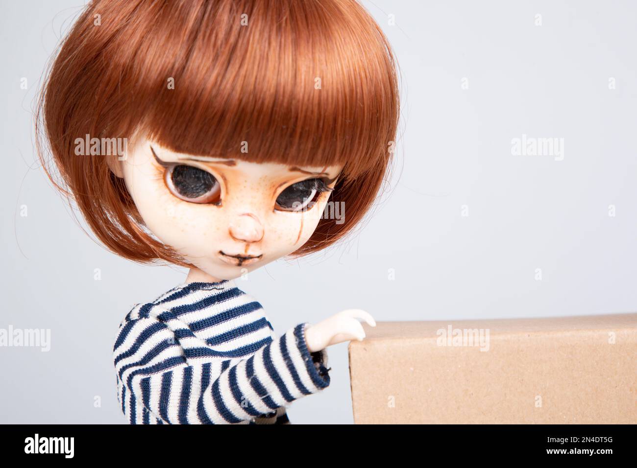 pretty portrait doll with big eyes red hairs in blue shirt in white