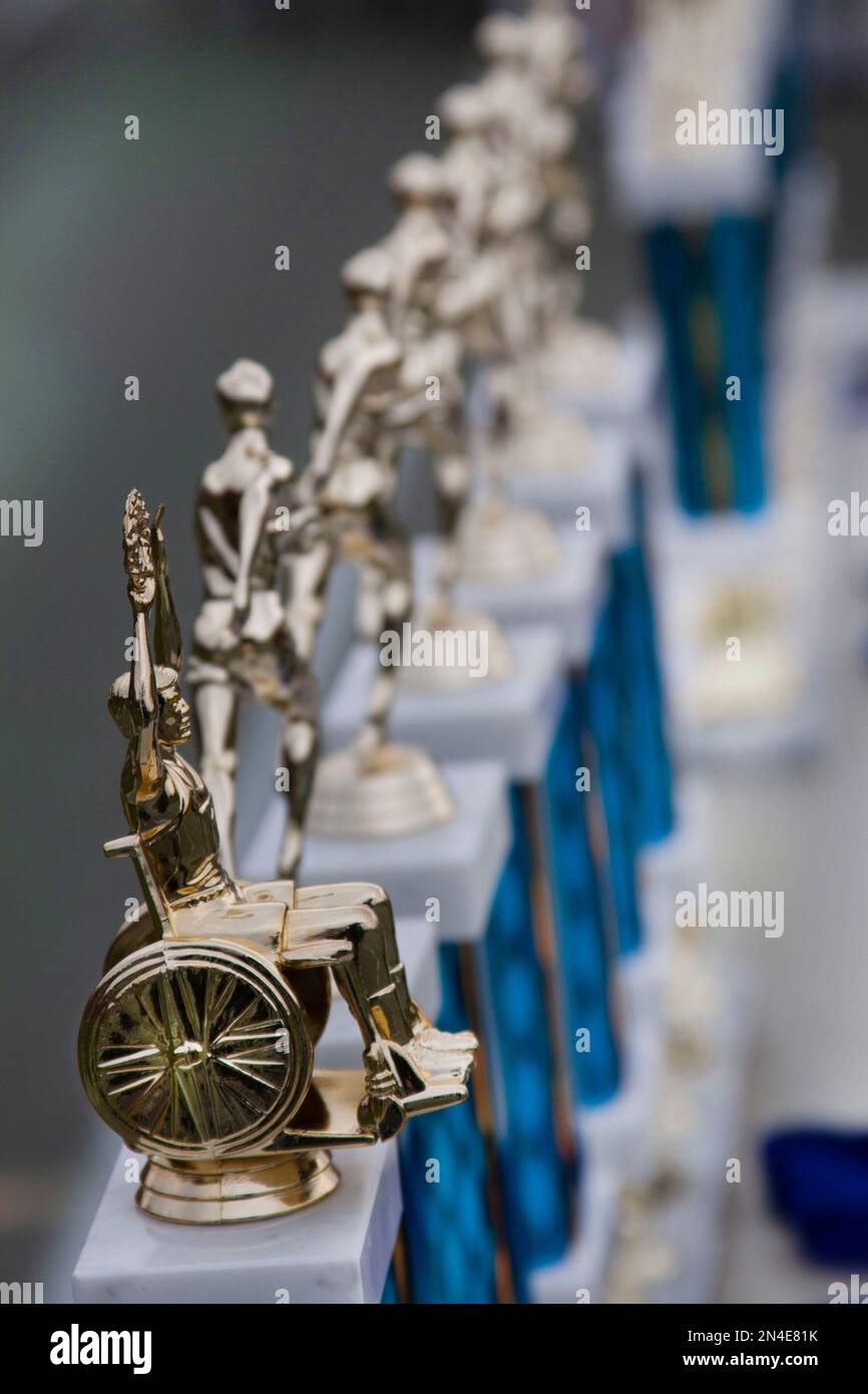 Row of Trophies, Trophy with Human Figure in Wheelchair in Foreground Stock Photo