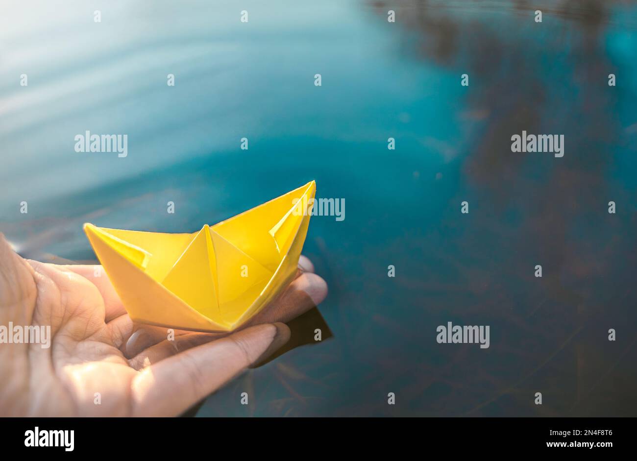 Yellow lonely floating paper boat in hand. Colorful sailing ship in big ...