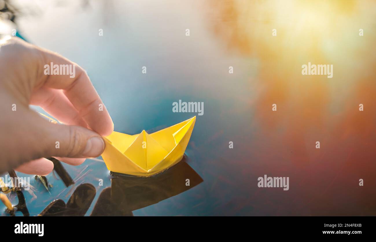 Yellow lonely floating paper boat in hand. Colorful sailing ship in big ...