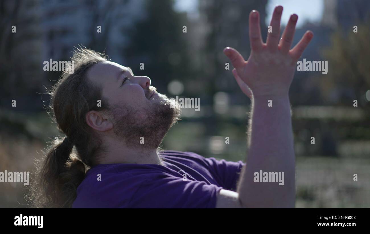 One Spiritual young man raising arms in the air asking for God help