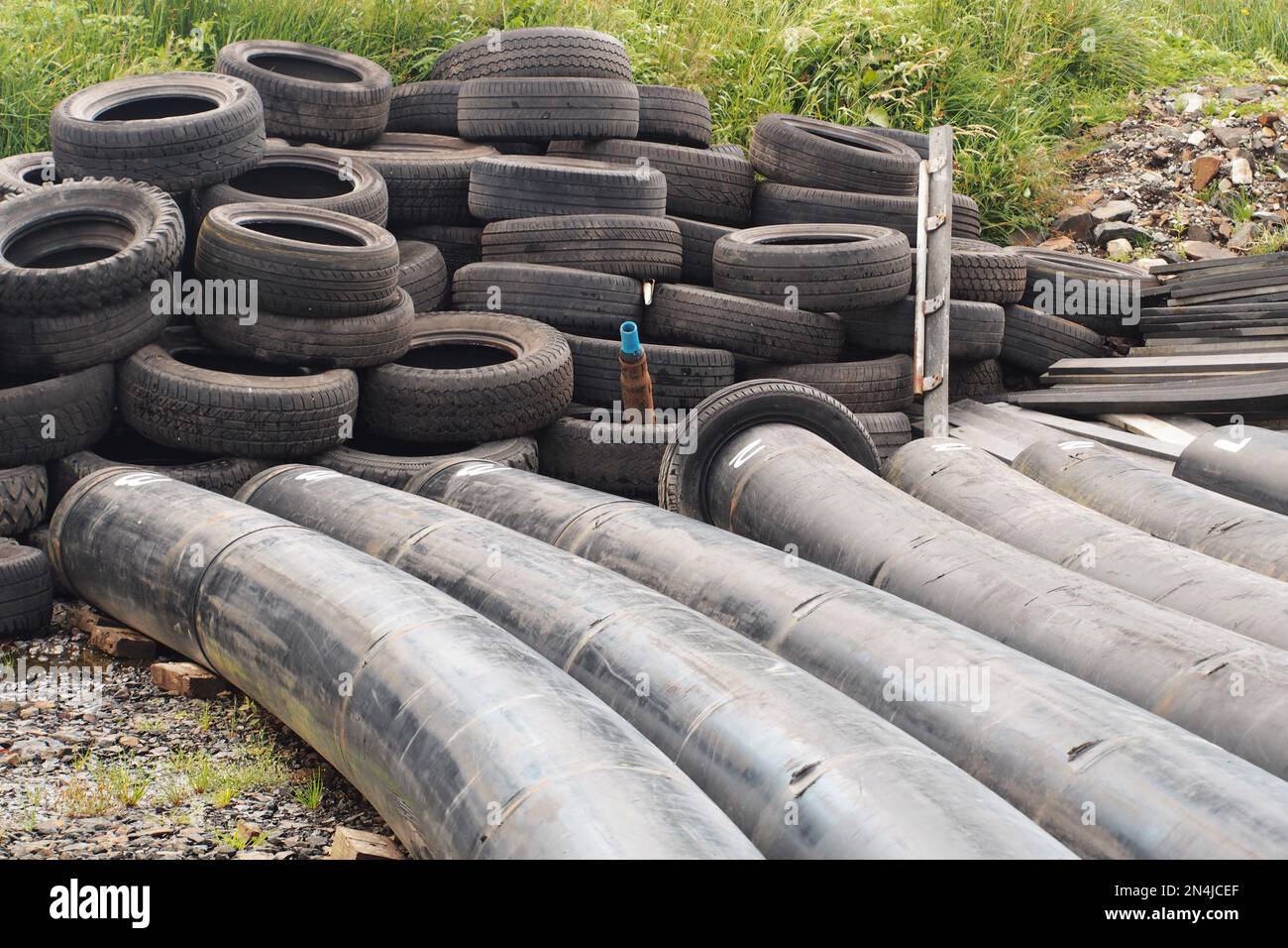 A pile of discarded old car tyes and booms lying on rough ground near the pier at Salen, Mull, Scotland Stock Photo