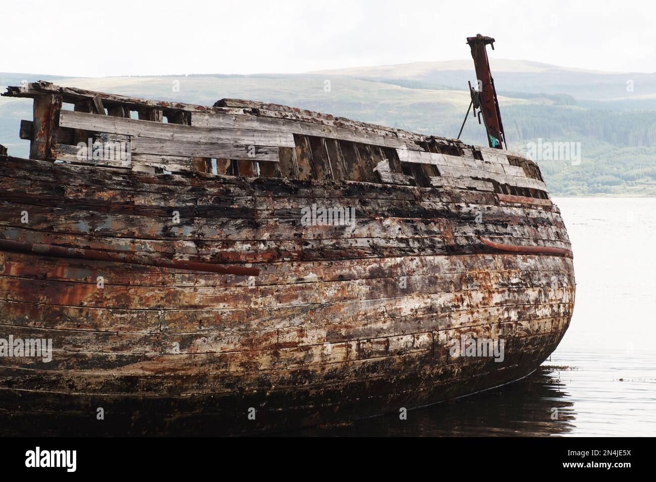 The hull of a long wooden ship leaning to one side, decaying and