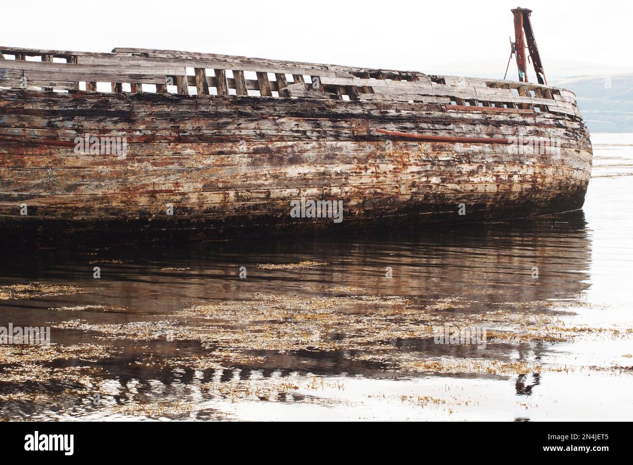 The hull of a long wooden ship leaning to one side, decaying and