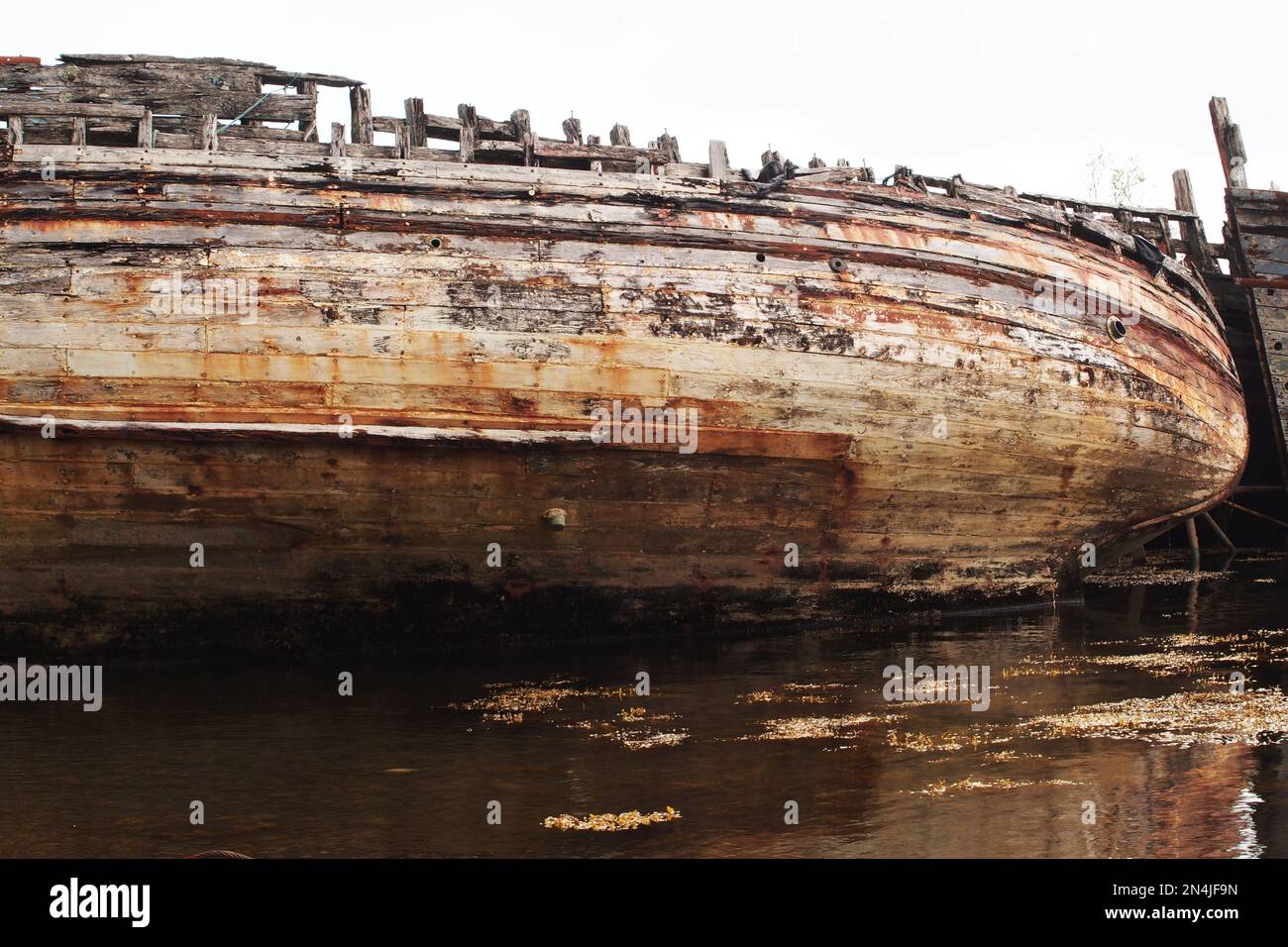 The hull two long wooden ship leaning to one side, decaying and rotting