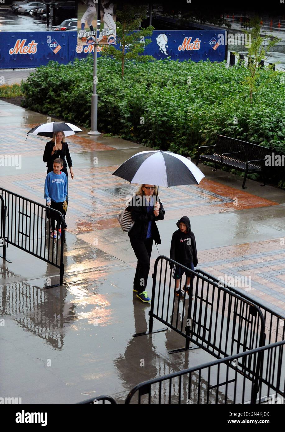Umbrella clad Mets fans walk the rainsoaked sidewalks outside Citi