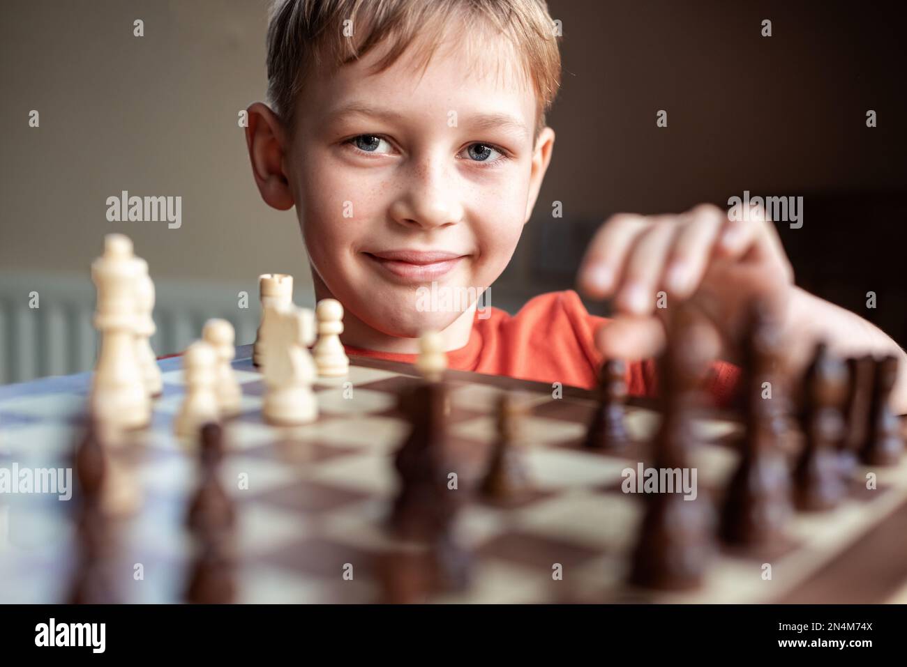 Pupil kid thinking about his next move in a game of chess. Concentrated  little boy sitting at the table and playing chess Stock Photo - Alamy