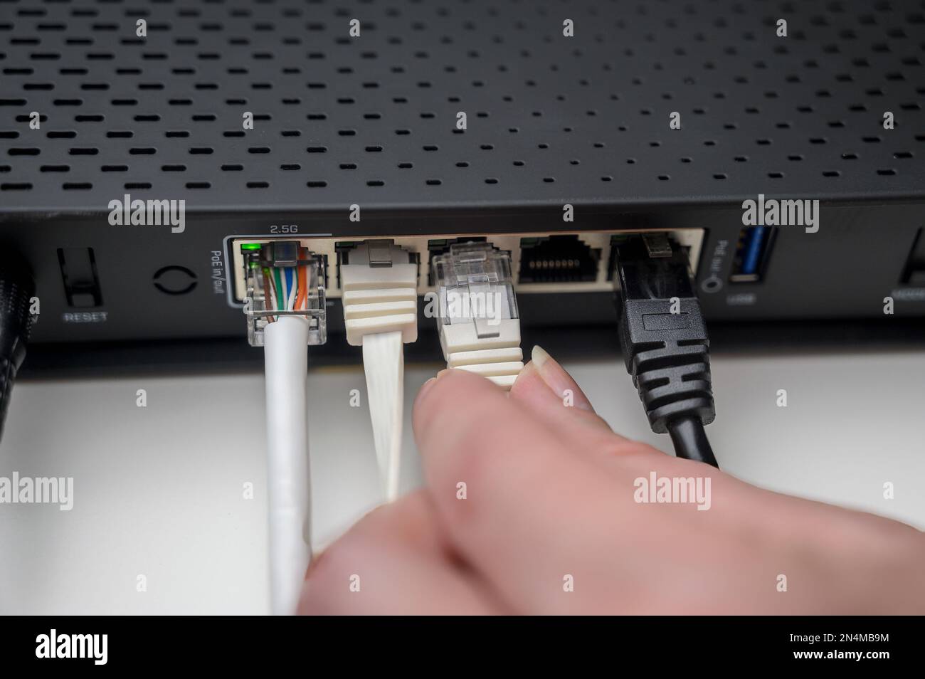 Woman's hand connects internet cable to LAN wired network switch