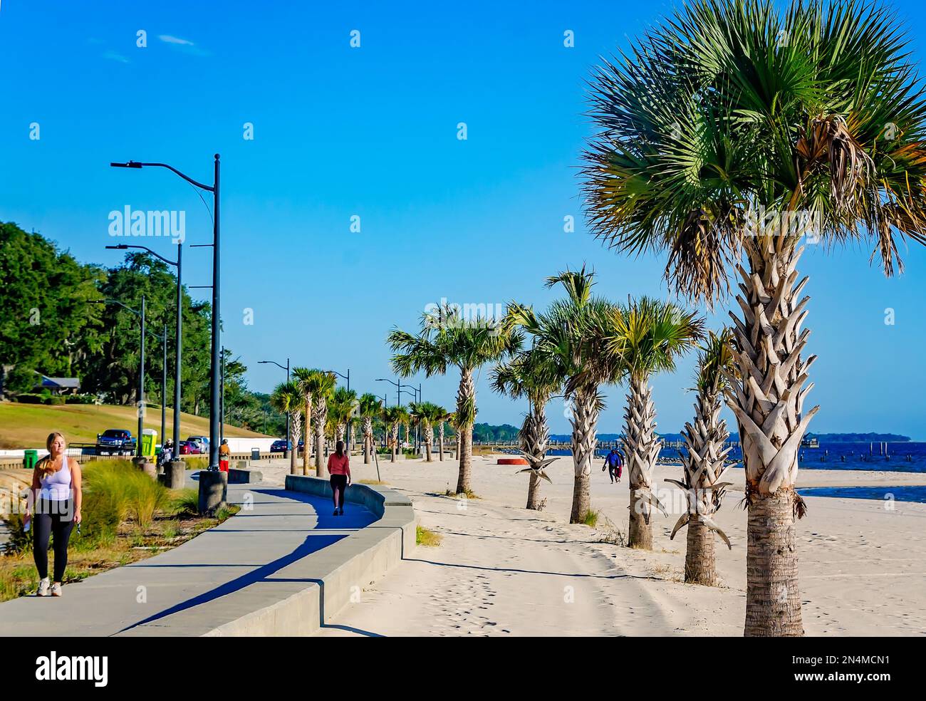 People walk along Front Beach, Dec. 28, 2022, in Ocean Springs, Mississippi. The 2.2 mile walking trail offers views of the Gulf of Mexico. Stock Photo