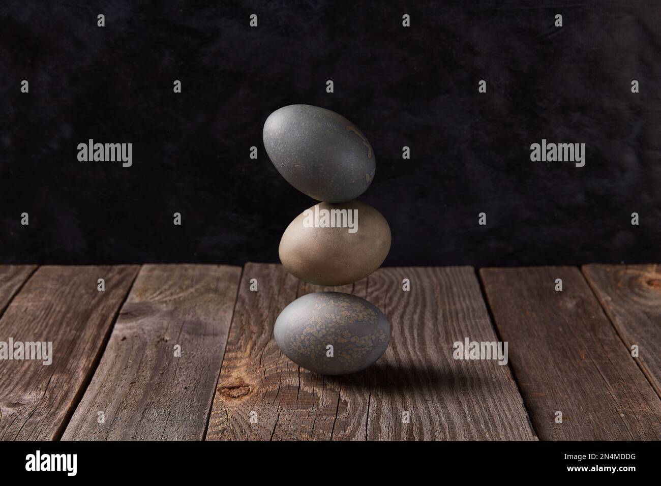 Balancing dyed eggs on wooden table. Easter celebration concept Stock Photo