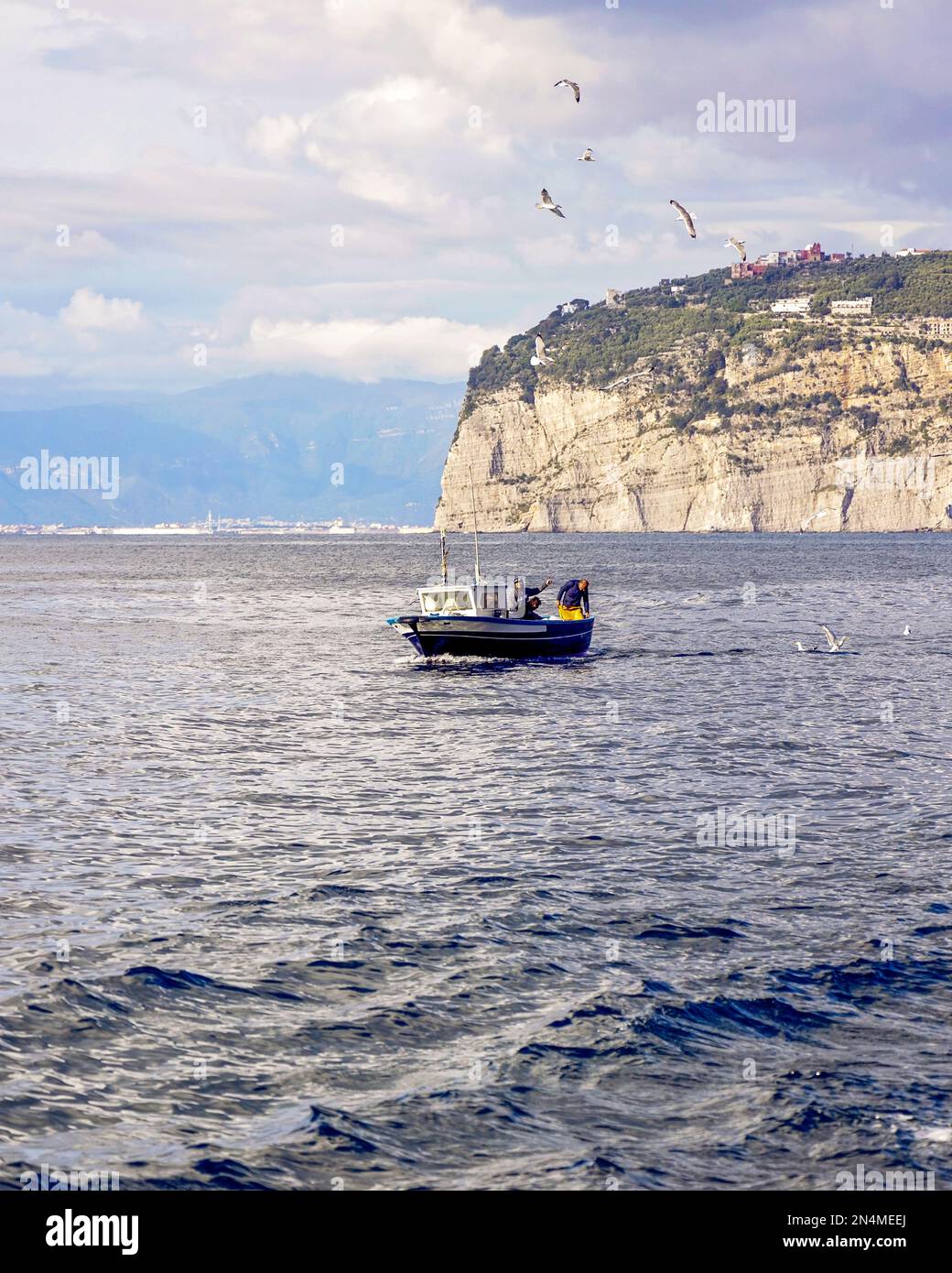 Sorrento, Italy - Fisherman on his boat getting fresh seafood in Naples Bay. Food is then cooked and served in a local restaurant in Sorrento, Marina . Stock Photo