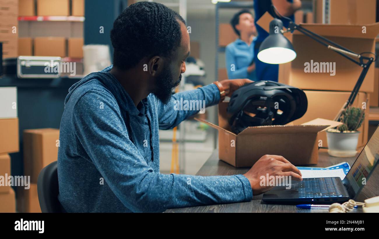 African american worker analyzing quality of merchandise in warehouse, preparing products order