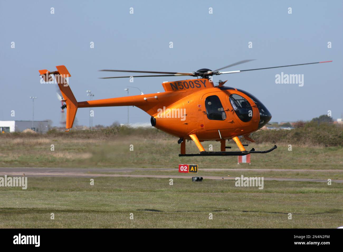 A McDonnell Douglas MD-500E helicopter takes off at Brighton City Airport. Lancing College to the rear Stock Photo