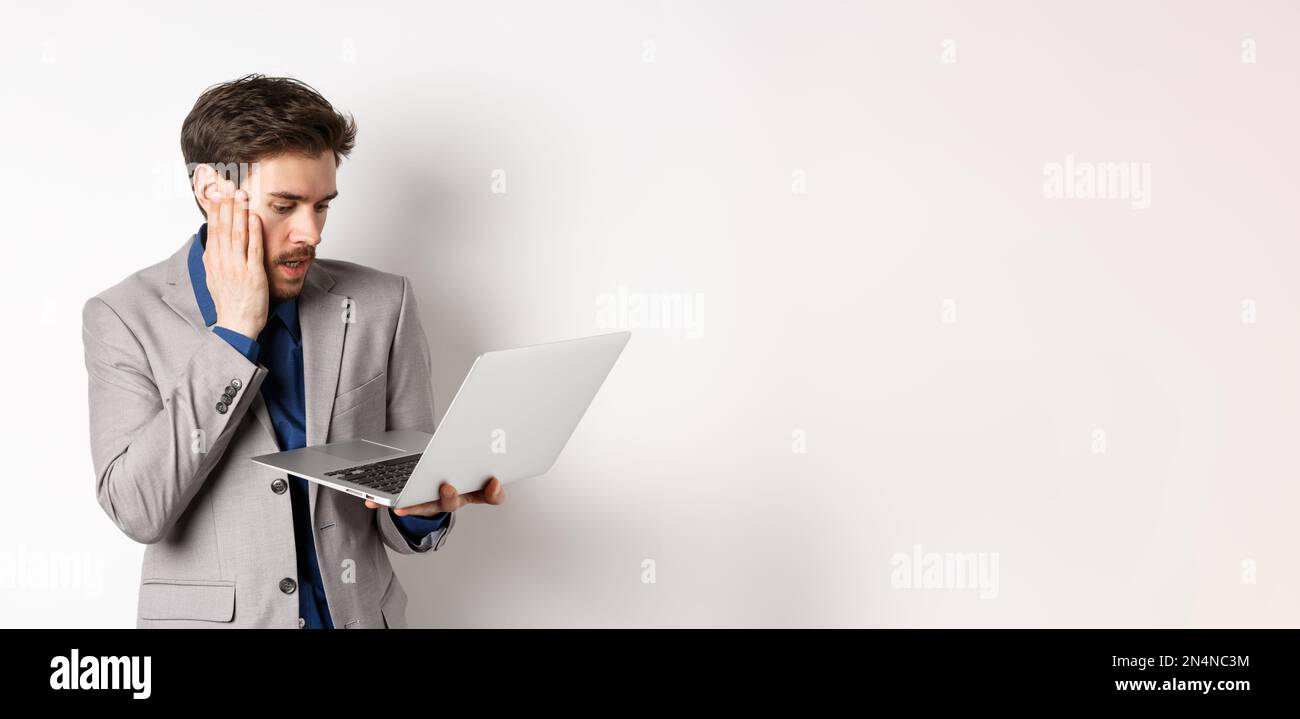 Shocked and worried businessman making mistake on laptop, looking at ...