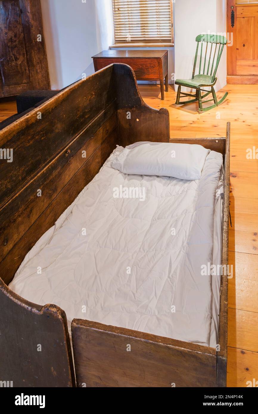 Opened pinewood 1830s beggar's bench bed and green wooden Boston rocking chair from 1880s in living room inside old circa 1750 home. Stock Photo