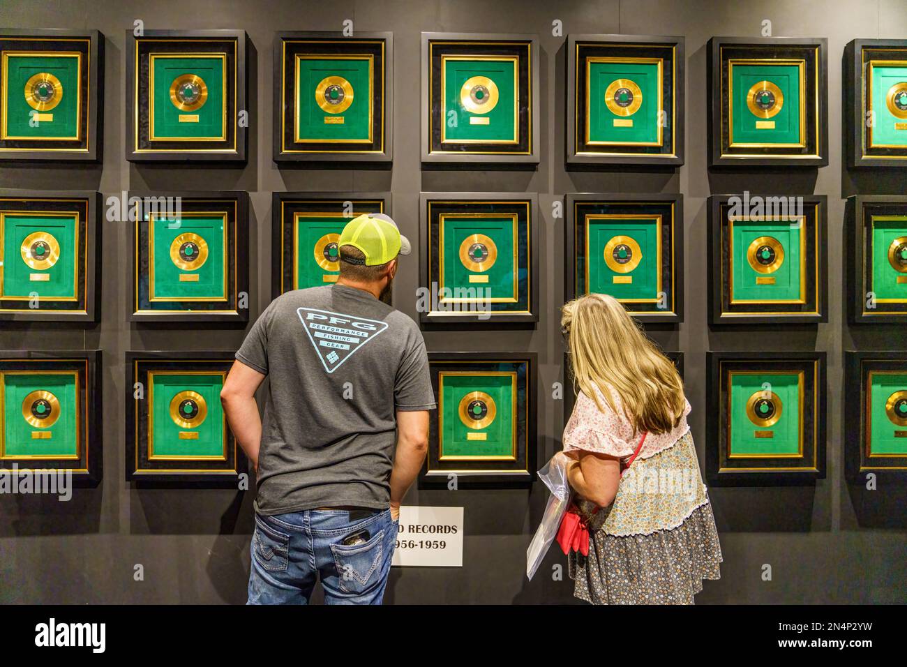 Couple looks at wall of Elvis Gold Records in the Elvis Presley's Memphis Entertainment Complex at Graceland in Memphis, Tennessee. Stock Photo