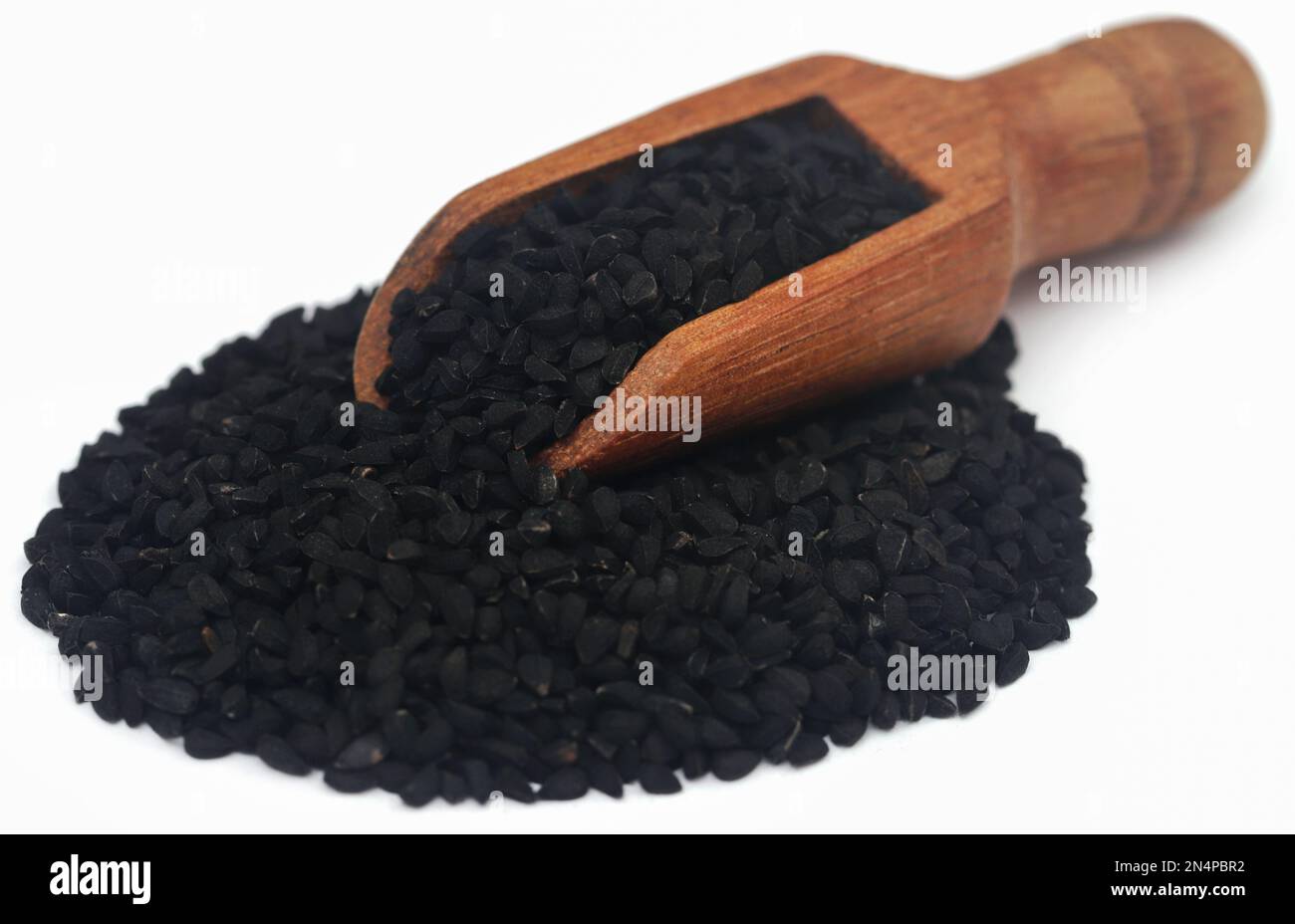 Nigella seeds with wooden scoop, over white background Stock Photo
