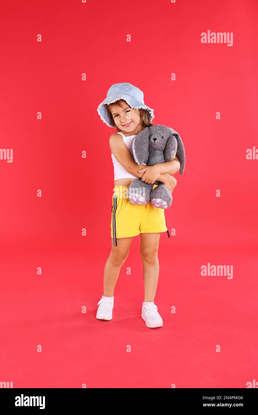 Cute little girl with toy rabbit on red background Stock Photo - Alamy