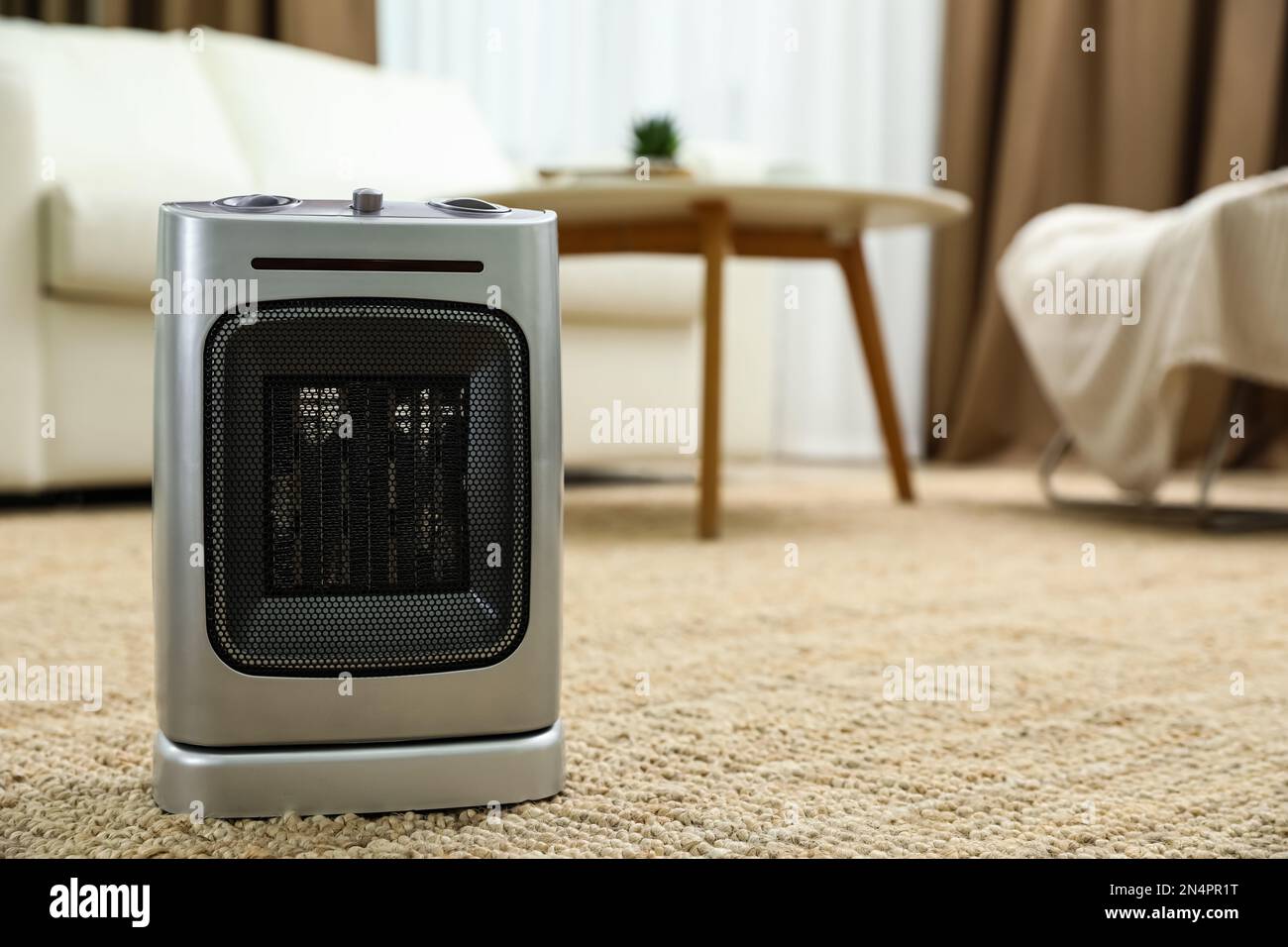 Modern electric fan heater on floor at home. Space for text Stock Photo
