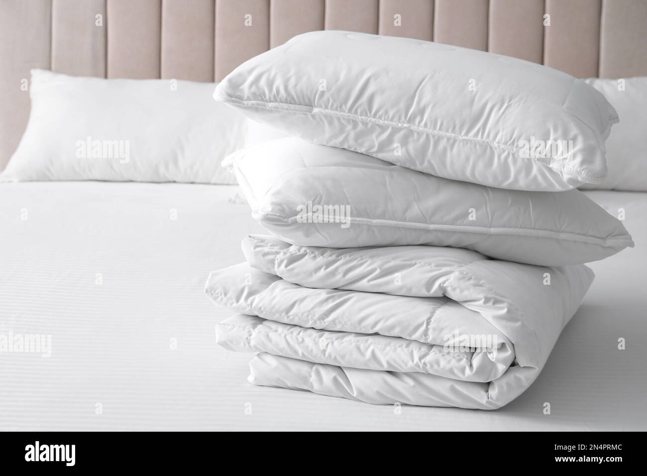Soft folded blanket and pillows on bed indoors Stock Photo