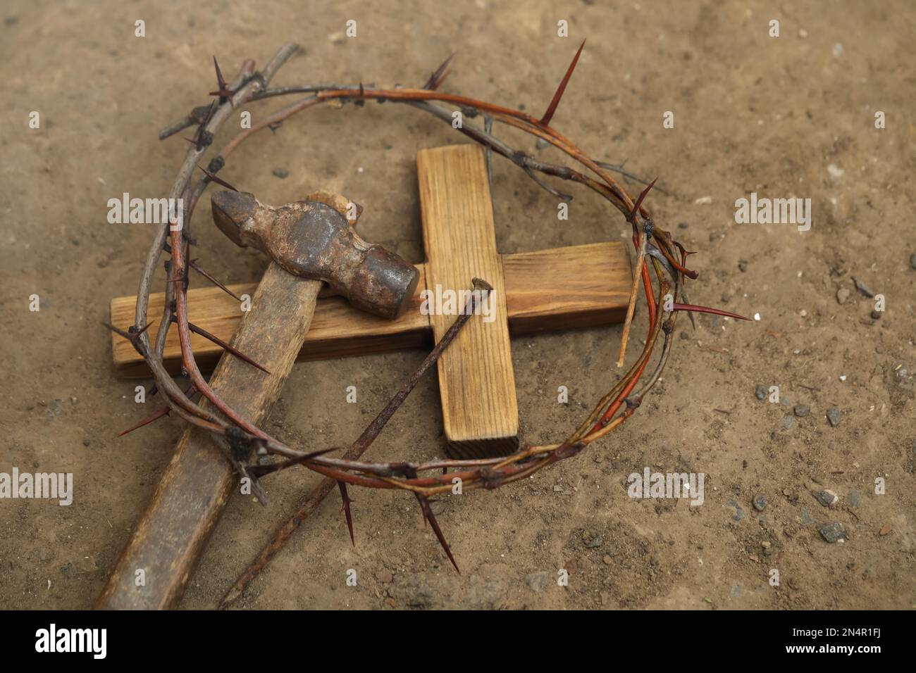 Crown of thorns, wooden cross and hammer with nail on ground, above view. Easter attributes Stock Photo