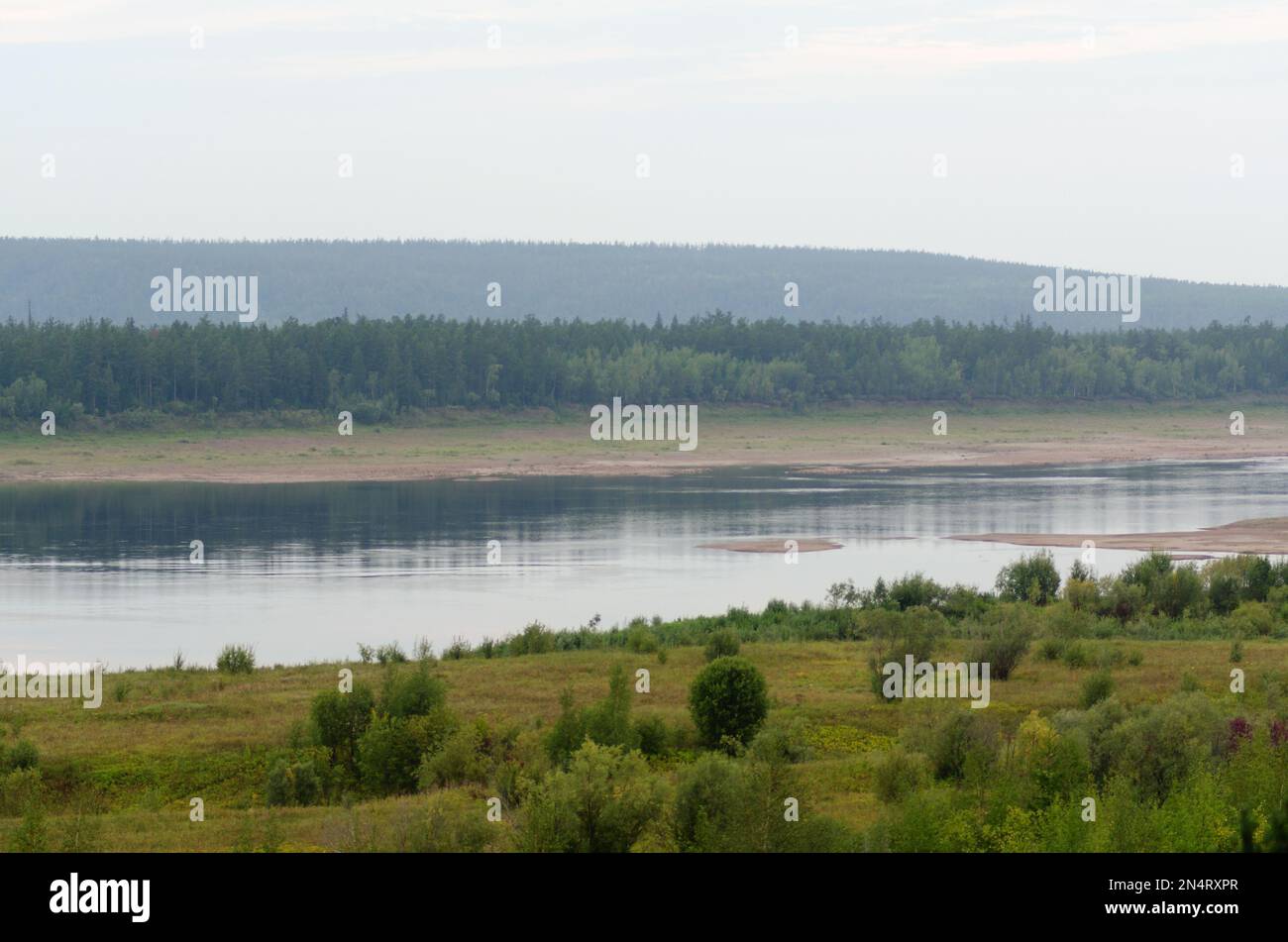 Wild Northern Yakut river Vilyui in Russia, flows through the tundra with overgrown banks on the background of spruce forests of the taiga summer day. Stock Photo