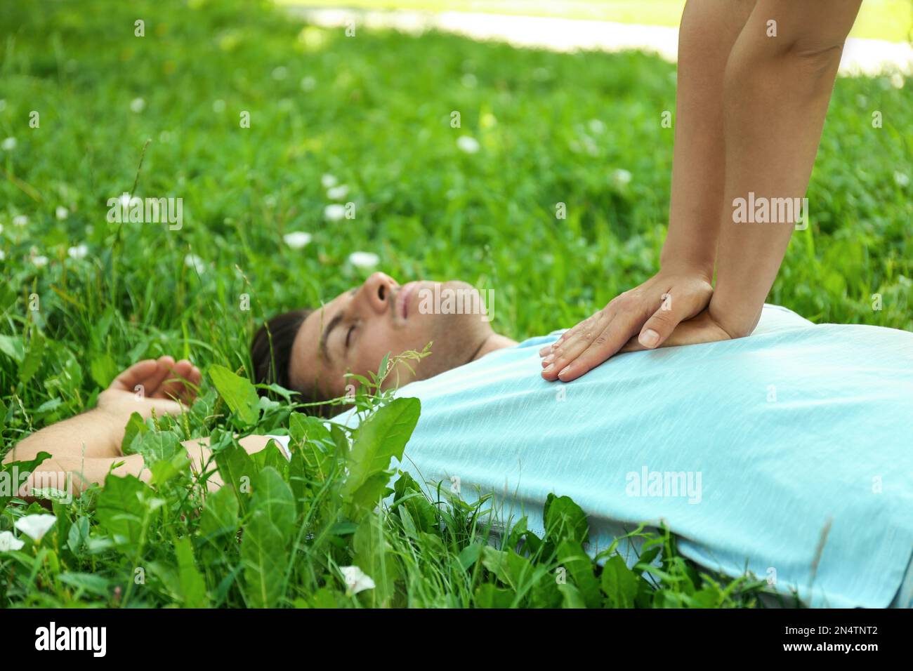 Young woman performing CPR on unconscious man outdoors, closeup. First