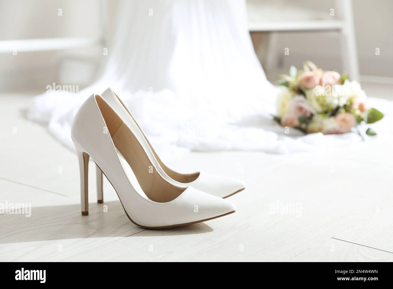 Pair of wedding high heel shoes on white wooden floor indoors Stock Photo