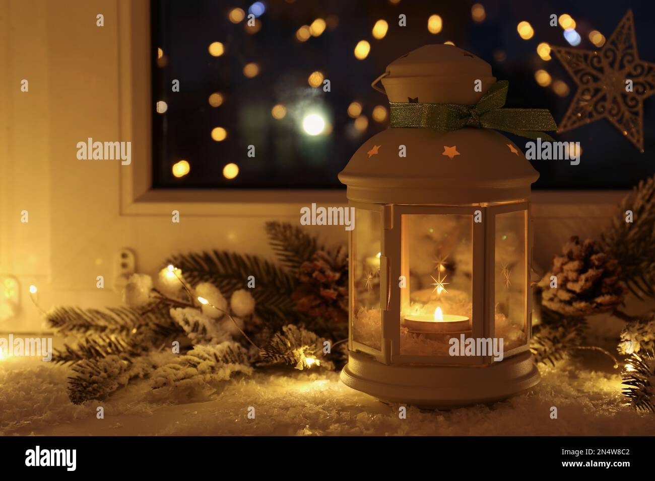 Beautiful Christmas lantern and other decorations on snowy window sill ...