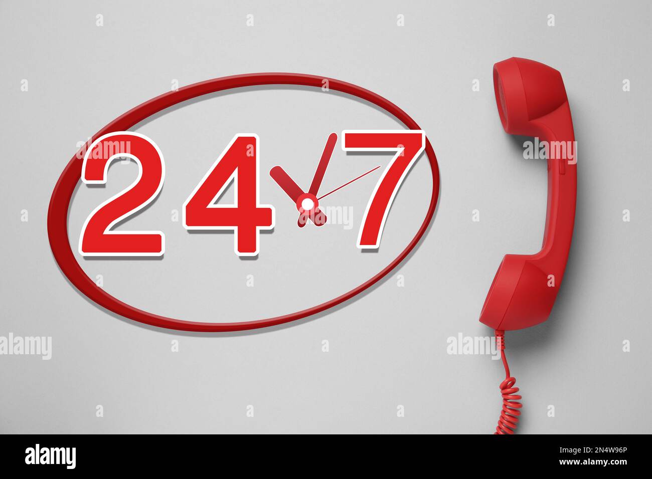 24/7 hotline service. Red handset on light grey background, top view Stock Photo