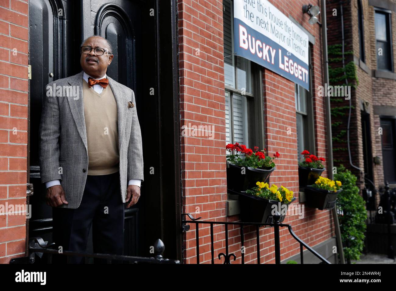 Trenton mayoral candidate Oliver "Bucky" Leggett stands in front of his  home, near a large banner Monday, May 12, 2014, in Trenton, N.J. Leggett, a  former deputy mayor in Philadelphia who later