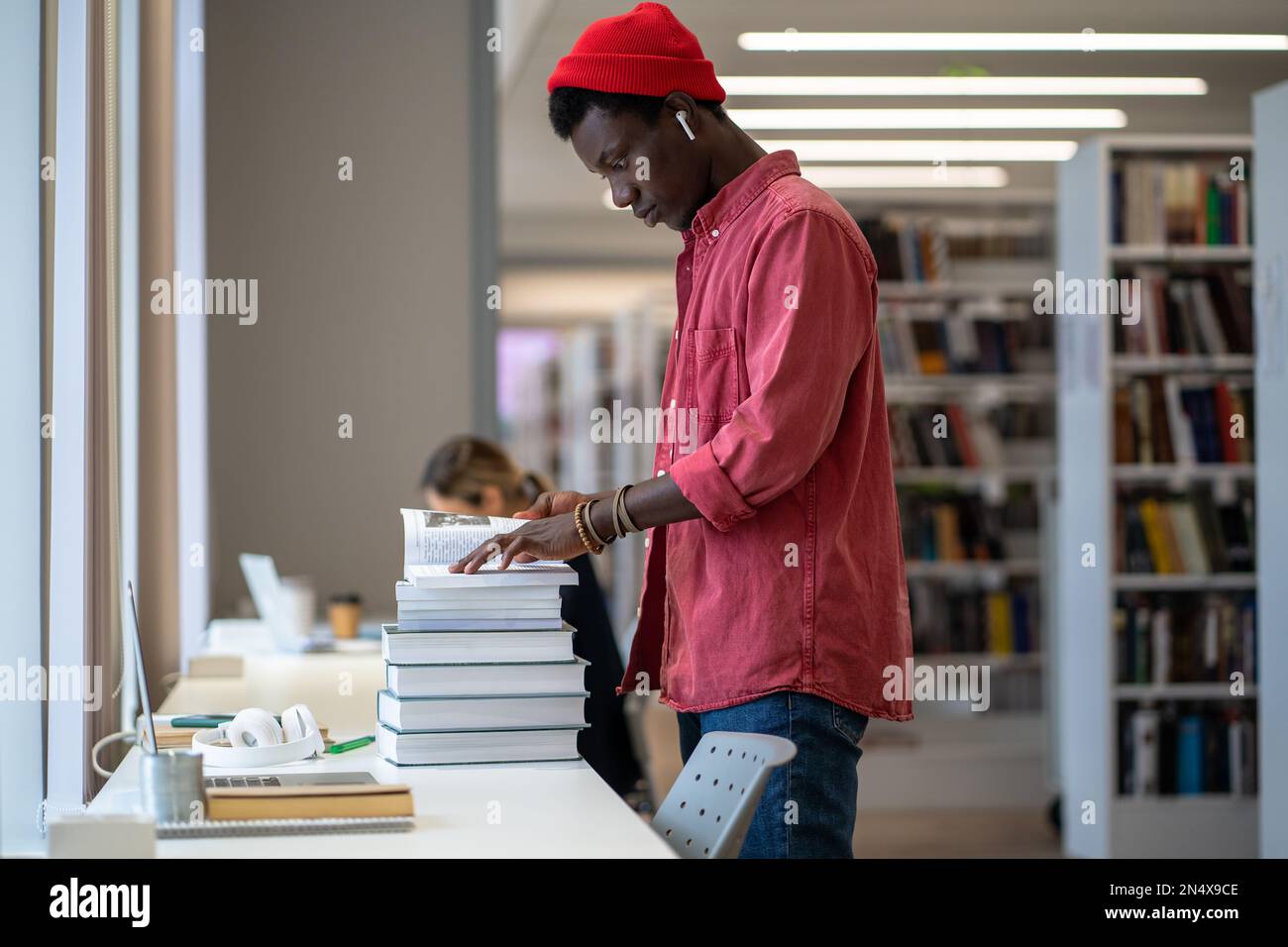 African American student guy standing in library looking for dissertation resources Stock Photo