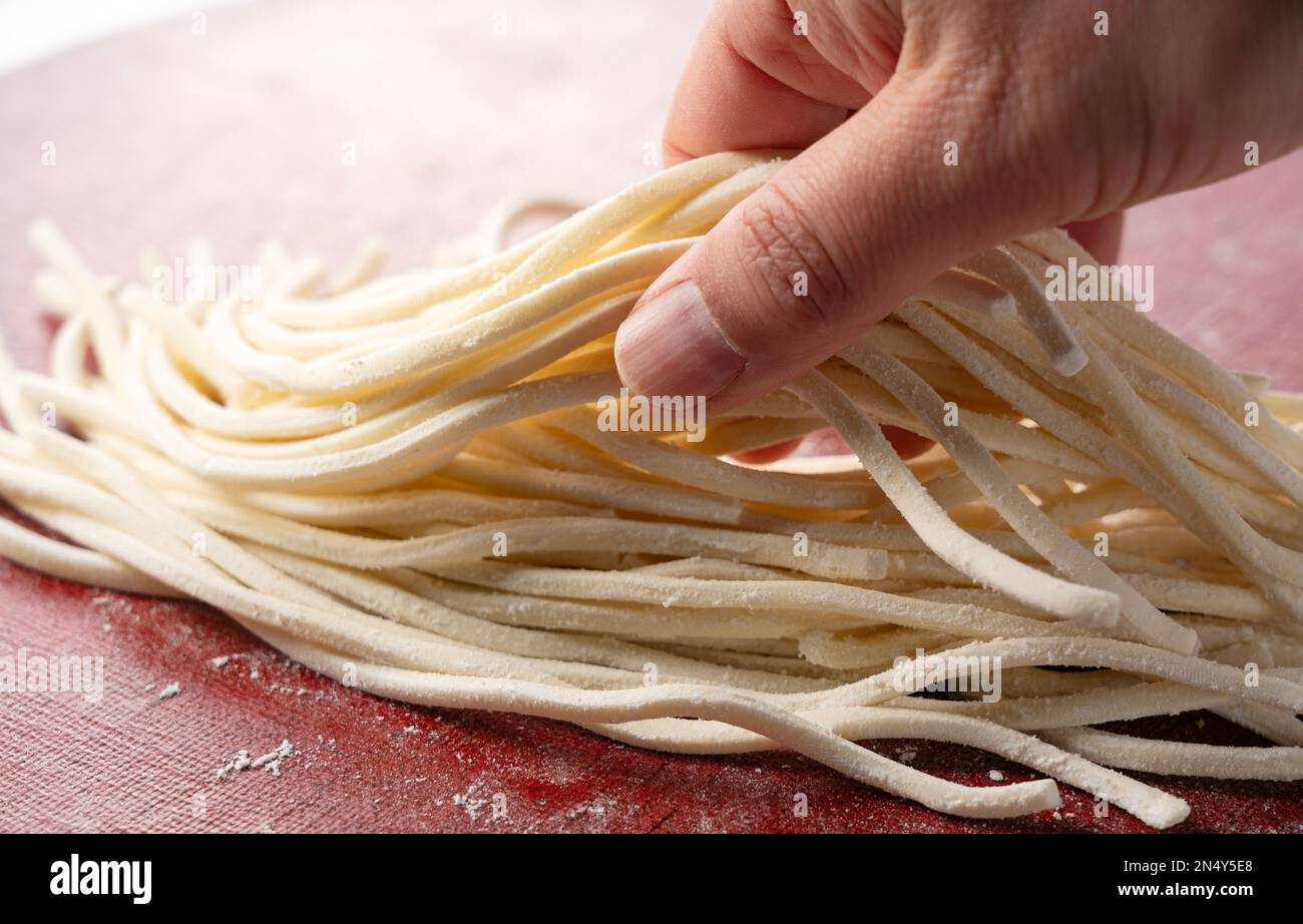 A man's hand holding fresh udon noodles. Udon noodles before boiling