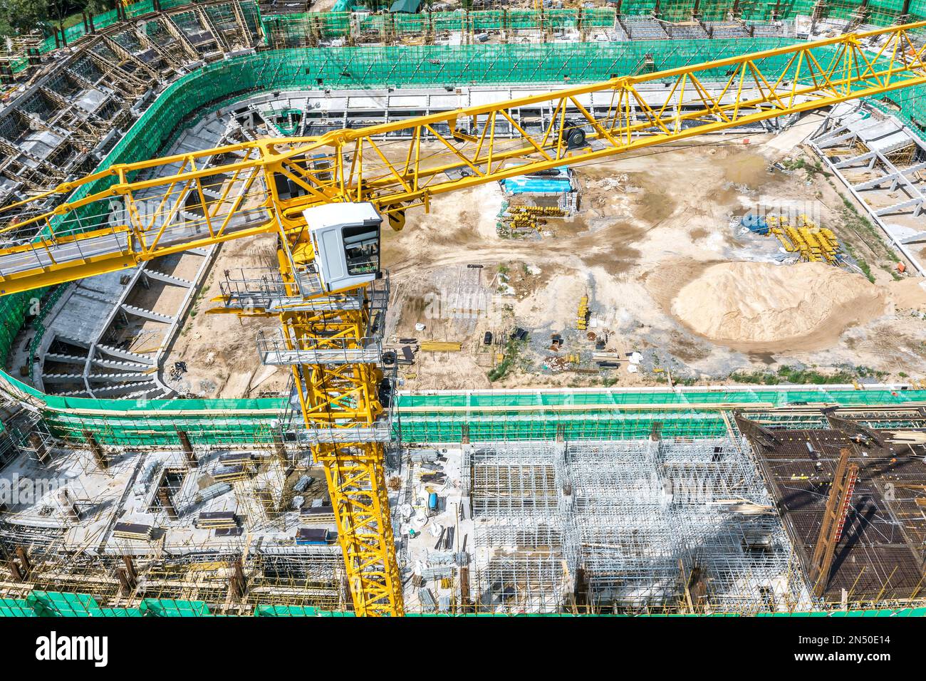yellow construction crane near the stadium under construction. aerial drone top down view. Stock Photo