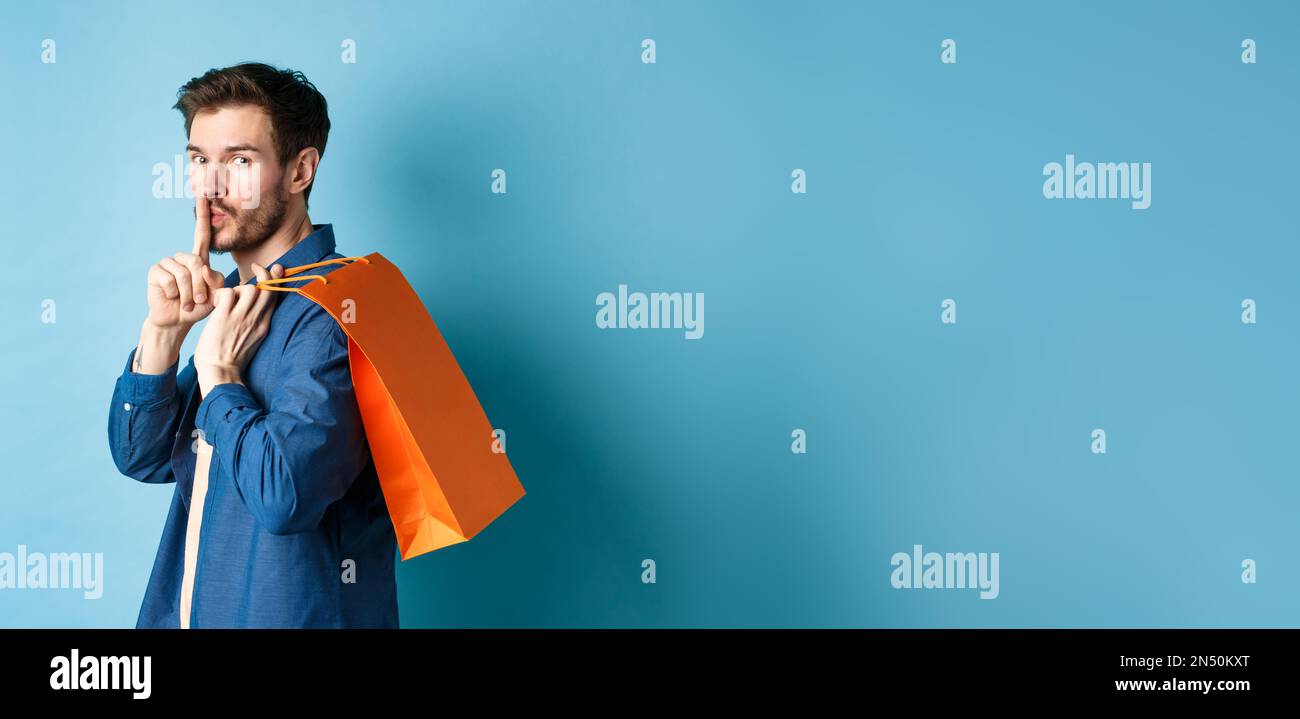 Image of modern guy holding shopping bag on shoulder, turn behind and ...