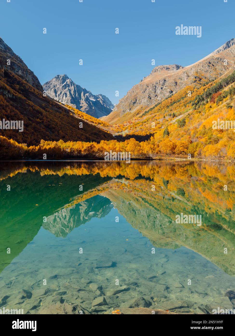 Quiet lake with transparent water and colorful autumnal trees ...