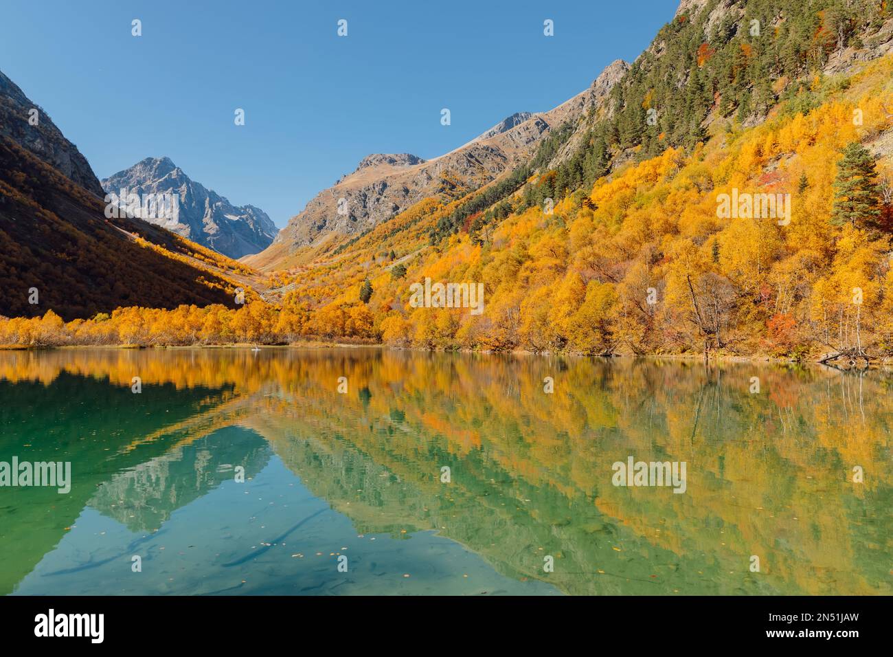 Quiet lake with transparent water and colorful autumnal trees ...
