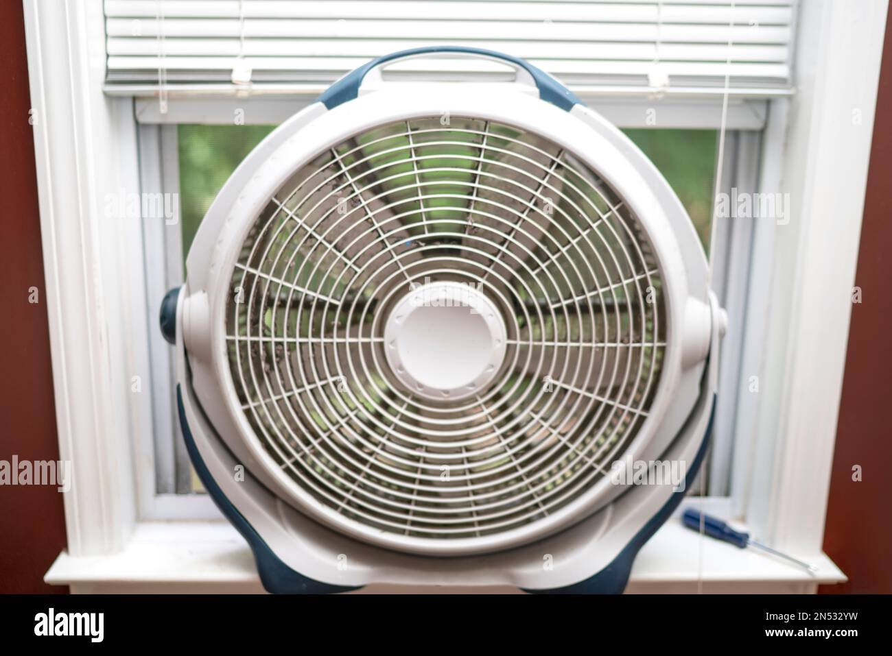 used dirty window fan dusty white round fan in window cool off Stock