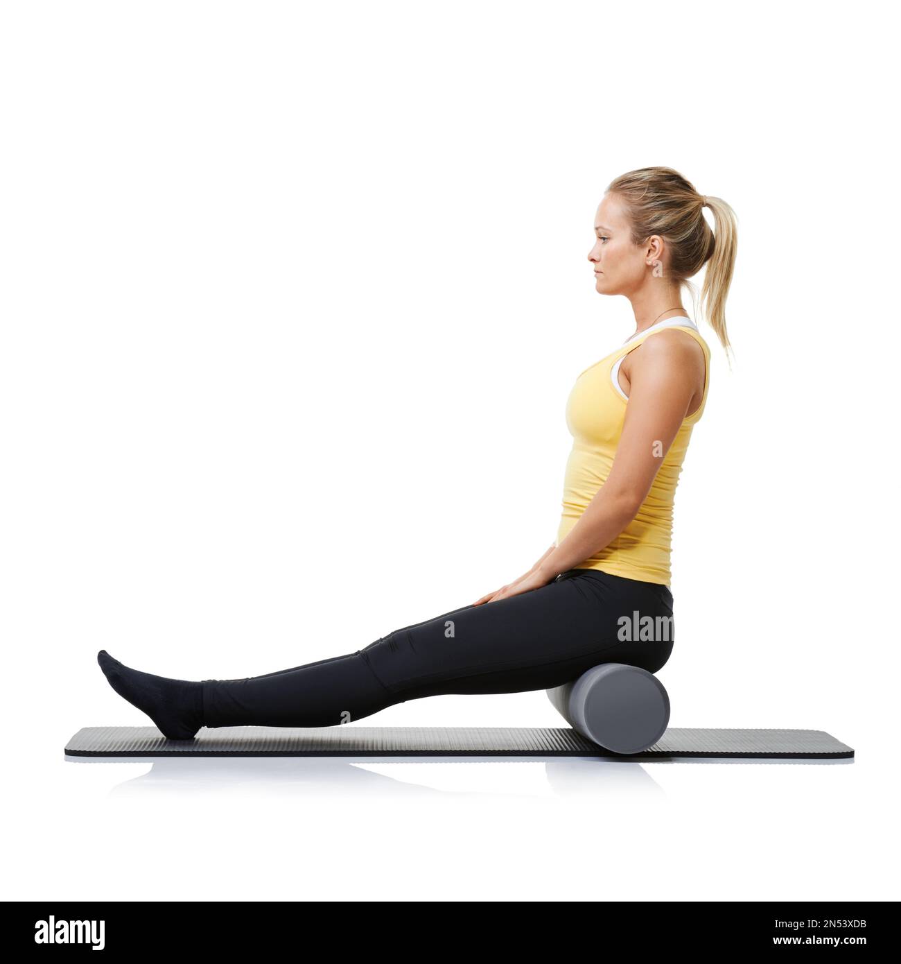 Focused. A young woman sitting on a foam roller and holding her ...