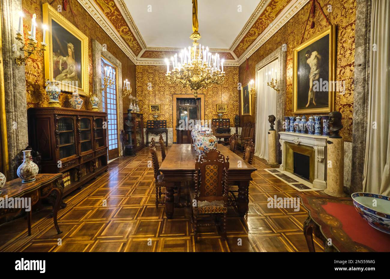 Dining room with heavy wood furniture, gold wallpaper and fireplace. At