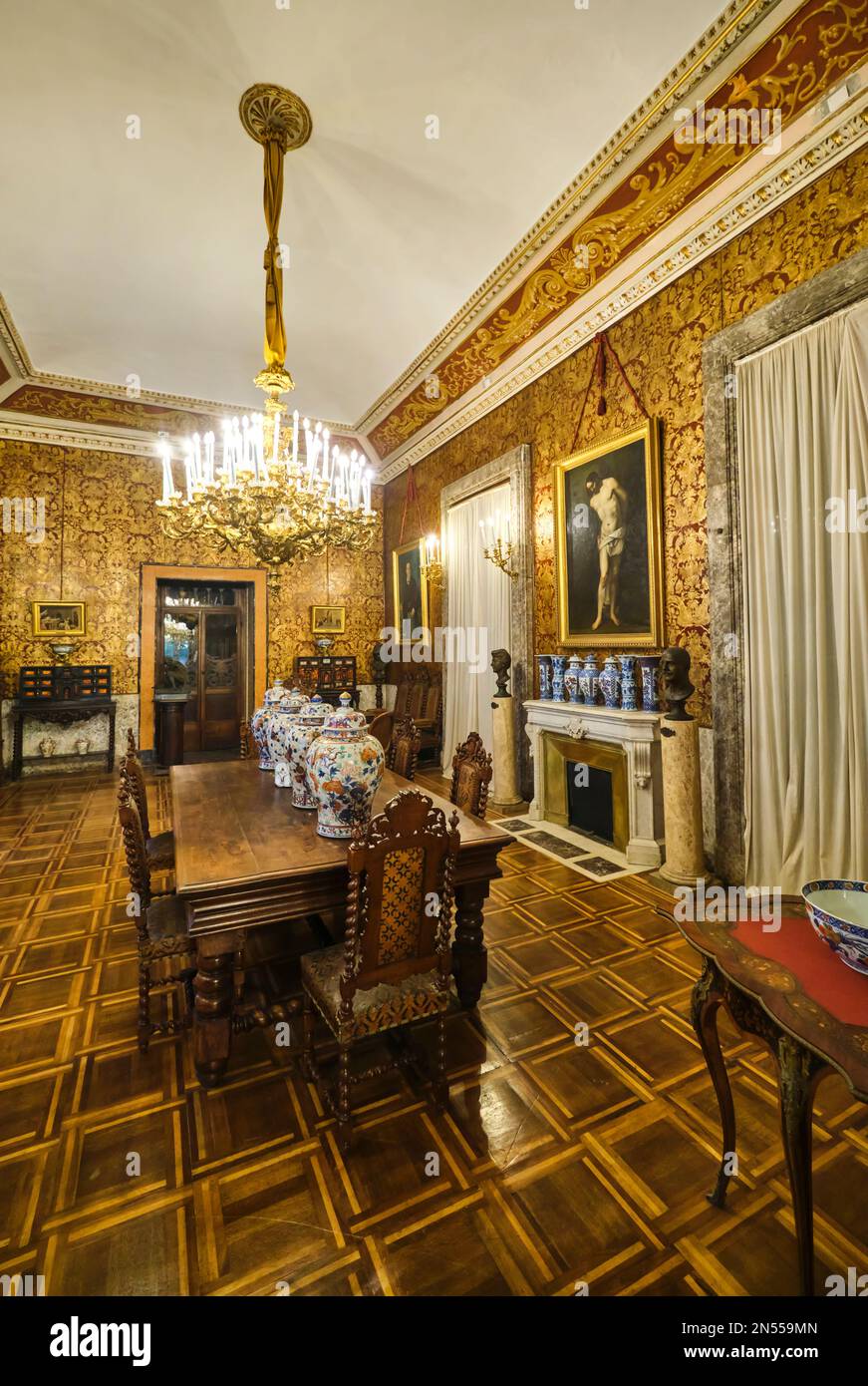Dining room with heavy wood furniture, gold wallpaper and fireplace. At