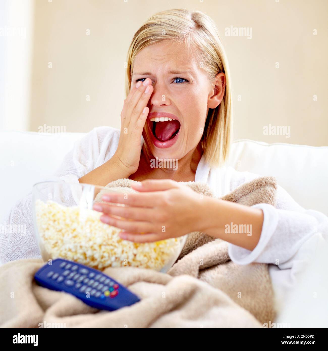 What a sad movie. A beautiful young woman watching a gruesome movie at home. Stock Photo