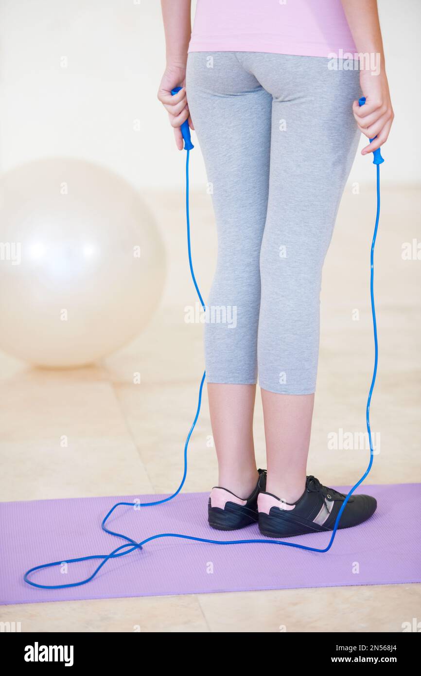 Readying for a hop and a skip. Rearview cropped shot of a young woman standing on an exercise mat holding a skipping rope. Stock Photo