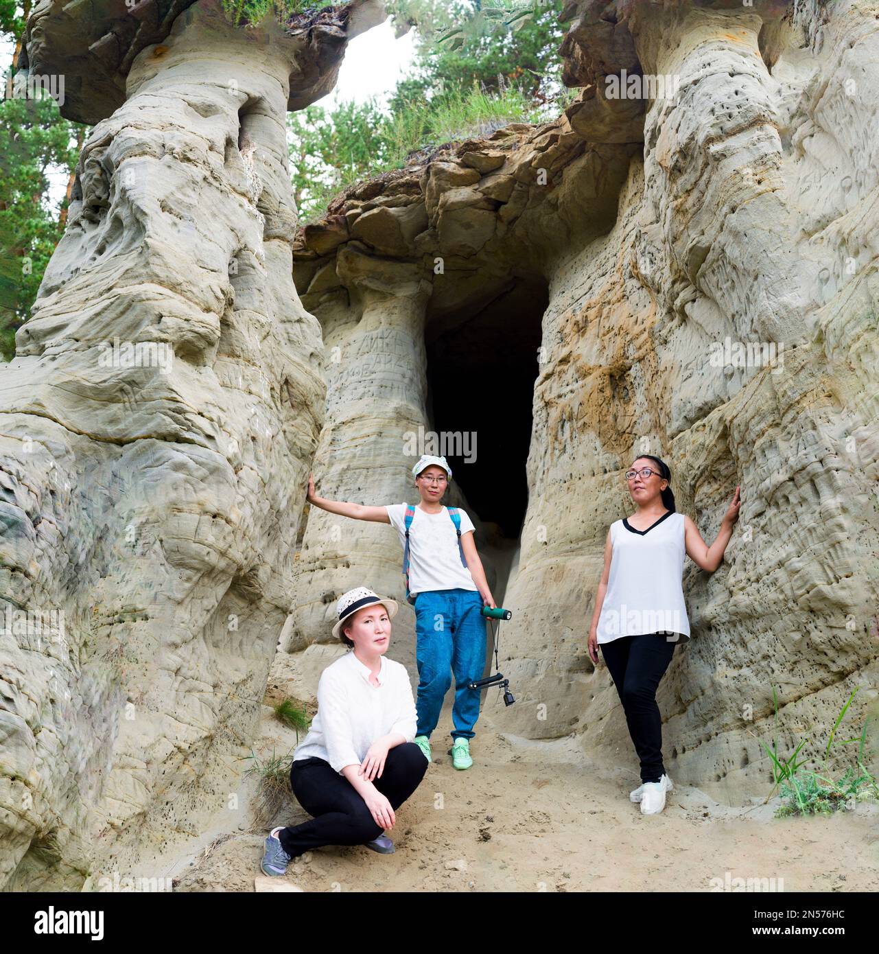 Three girls girlfriends tourists with camera in white t-shirts are worth have attractions Yakutia sand mushrooms and caves-errozitsionnykh forms terra Stock Photo