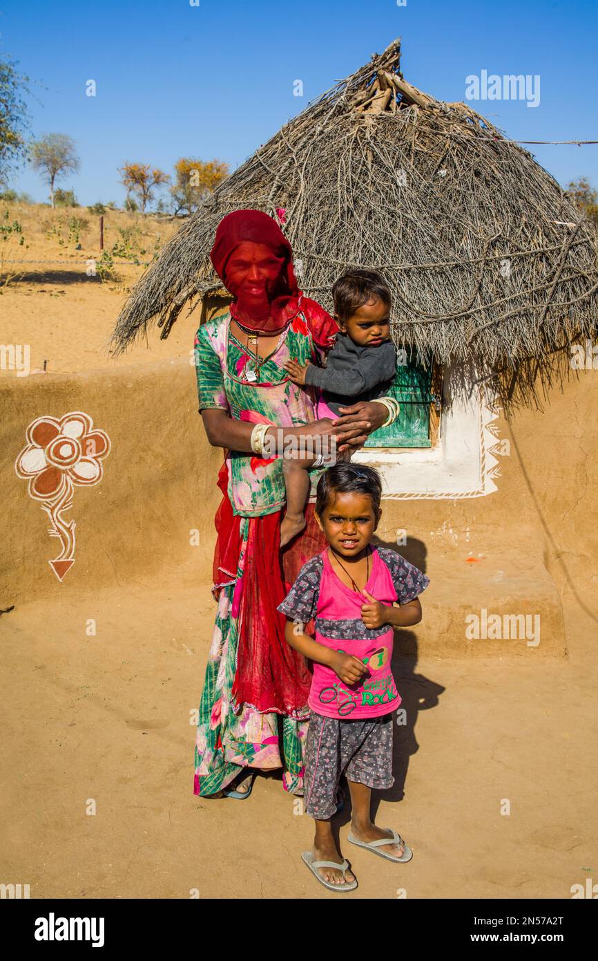 Colourfully dressed desert dwellers, mud hut settlement in the Thar Desert, Thar Desert, Rajasthan, India Stock Photo