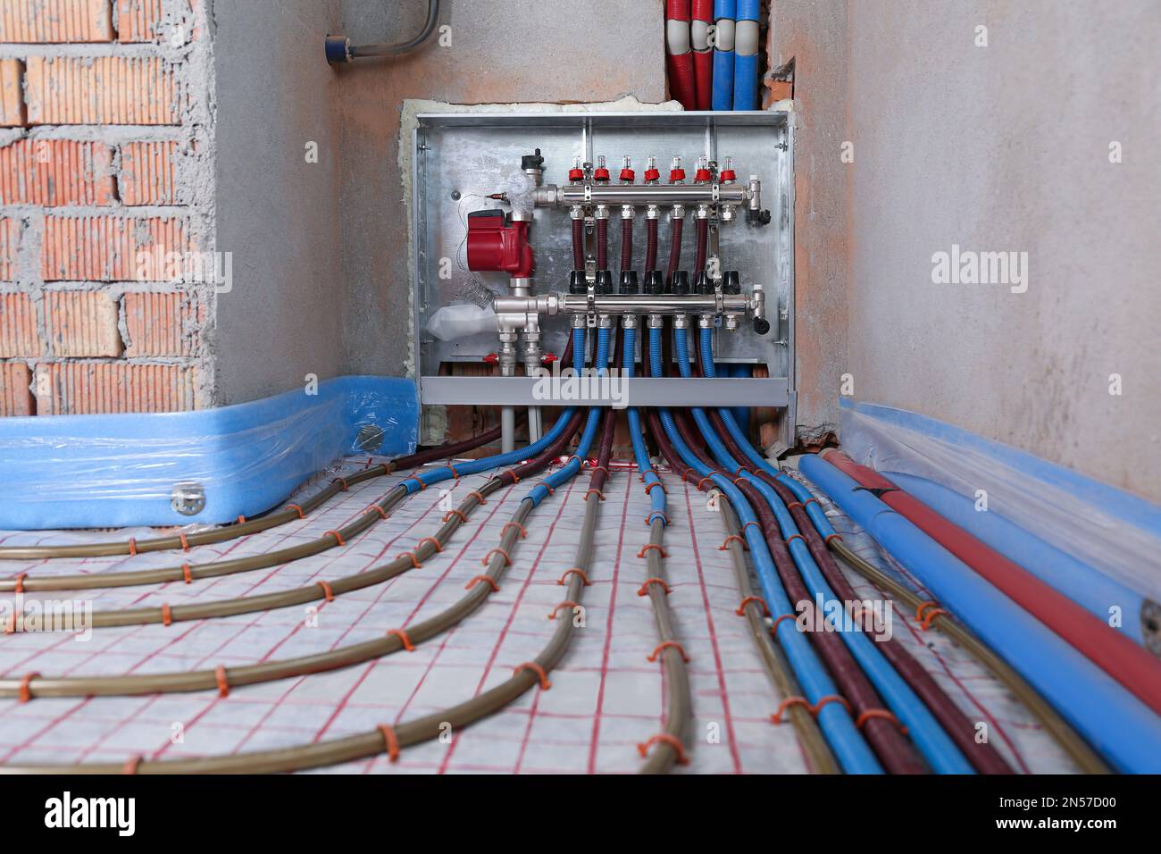 Underfloor heating system. Manifold with pipes in building Stock Photo