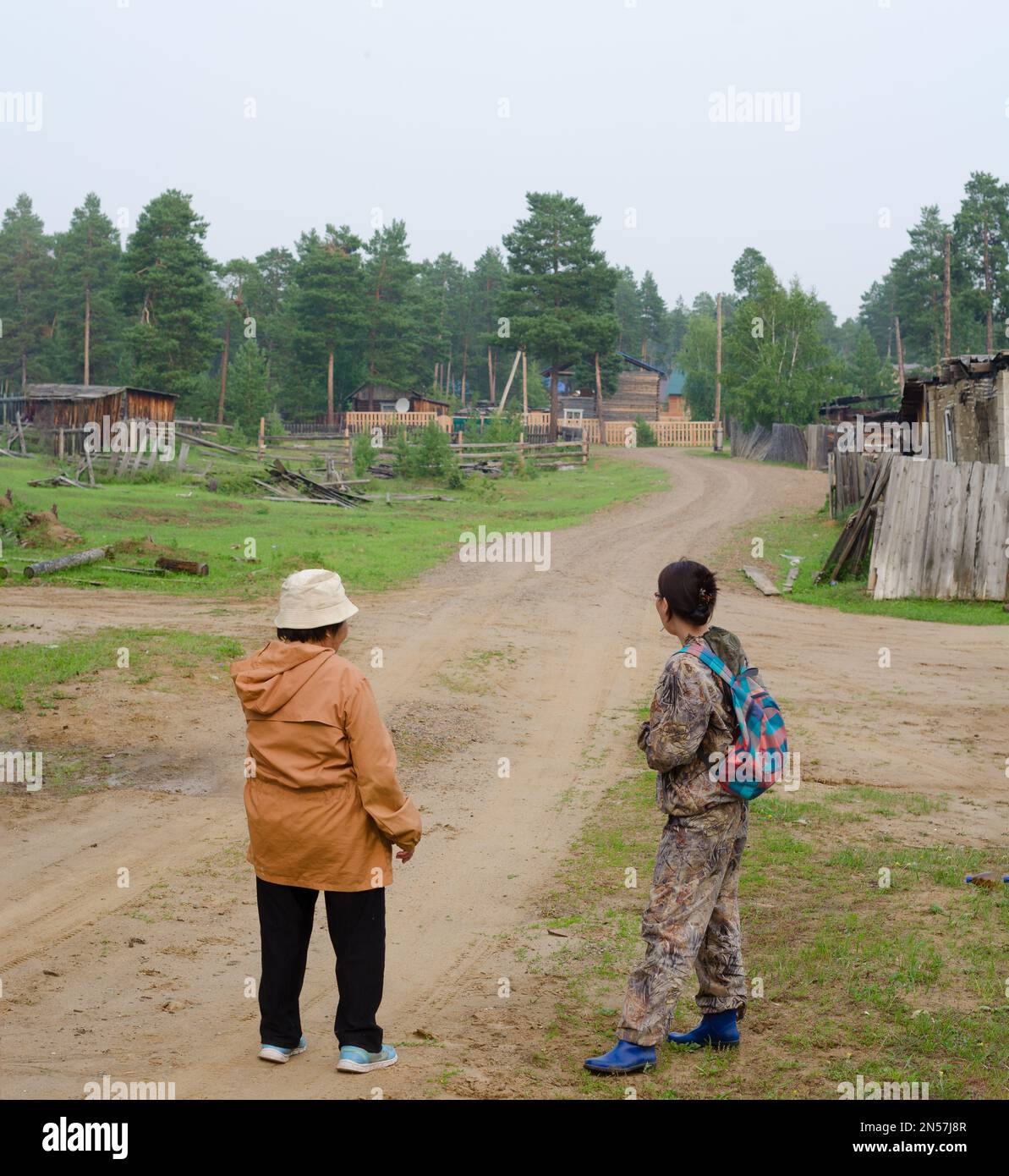 A Yakut couple an elderly woman in Panama and a young Yakut girl look at the country road to the villages near the forest before choosing a path. Stock Photo