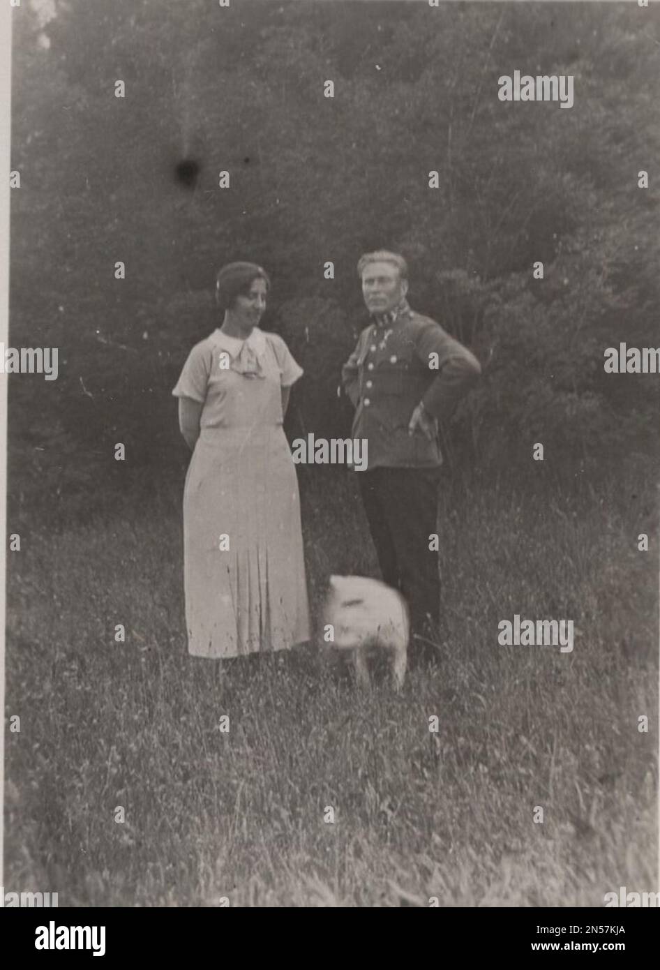 Vintage Photograph about a ( pet dog) high ranking miliary officer in uniform ( austro-hungarian officer? germany officer ? any other european military officer ) with his wife and them little white dog at the 1910s or 1930s Stock Photo