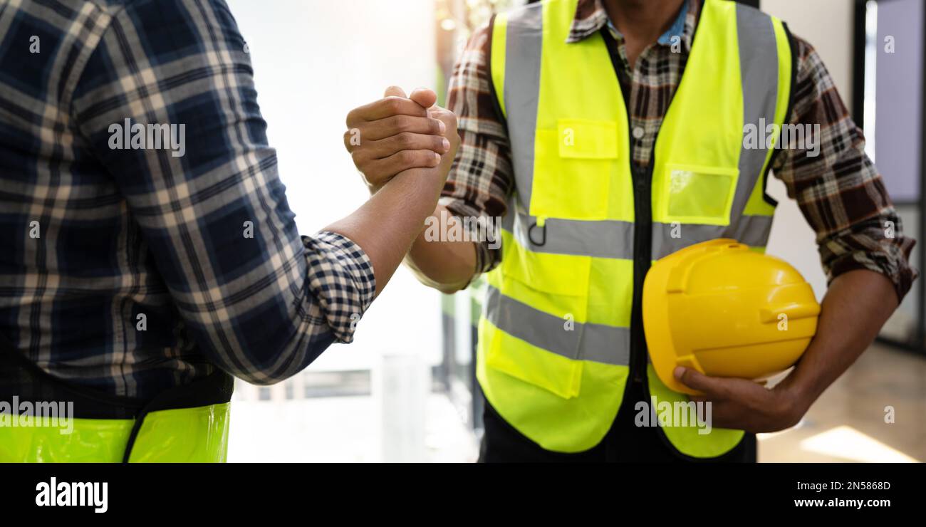 Construction engineer and architect with blueprint shaking hands while ...