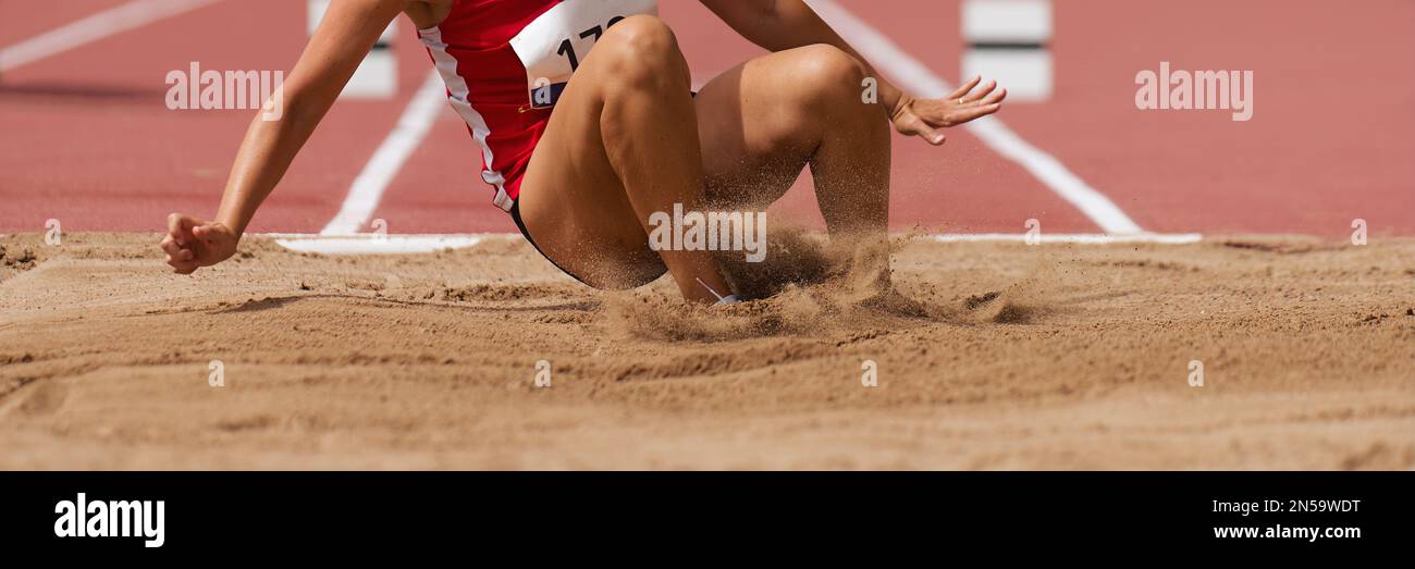 Female athlete long jump landing sand spray, landing in long jump in